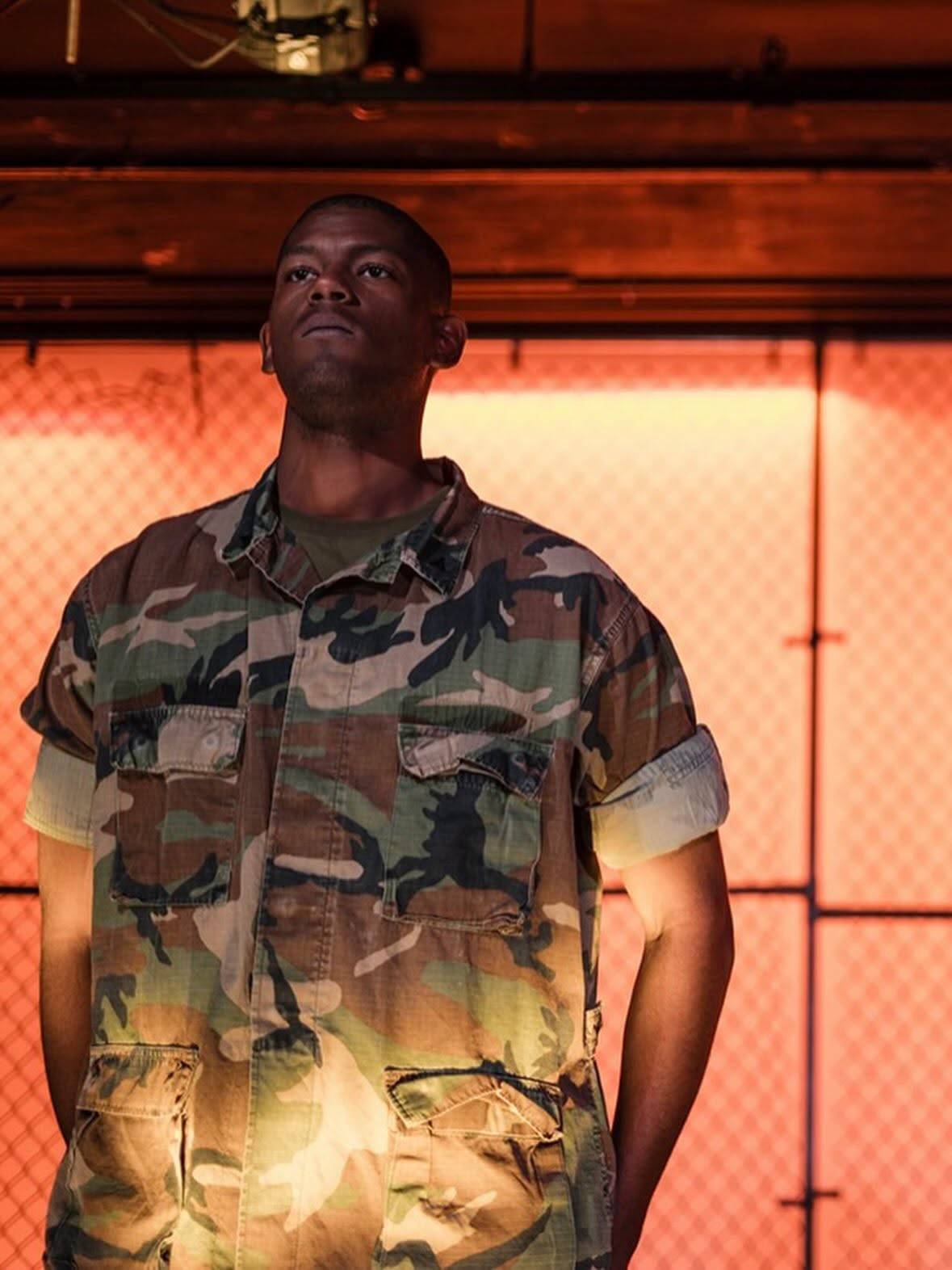 A performer in camouflage uniform stands at attention.