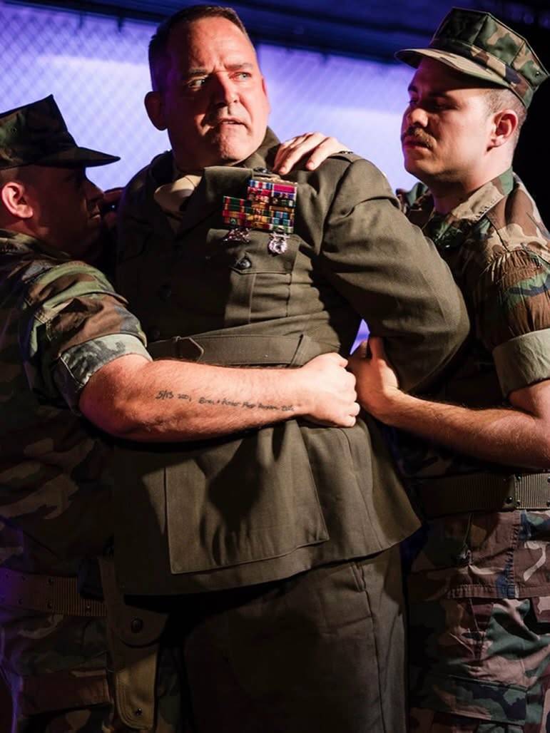 Two Marines restrain a commanding officer in uniform.